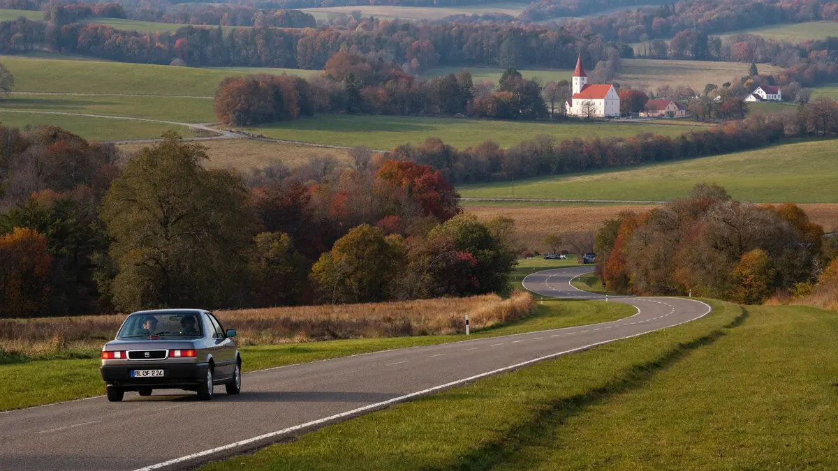 Samochód na wiejskiej drodze wśród pól jesienią